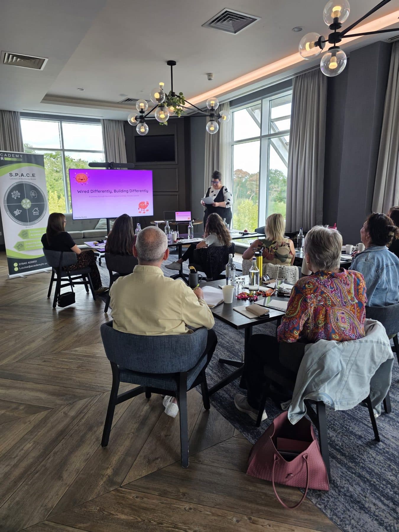 Charlie presenting Wired Differently, Building Differently to the room at Academy HR Executive Sessions, the title slide on screen